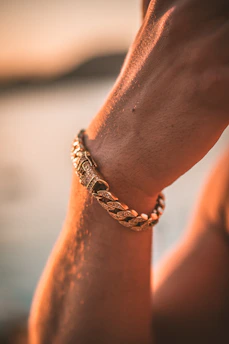 Close-up of a delicate 14k gold filled chain seamlessly micro-welded onto a wrist, glowing softly in warm golden hour light.