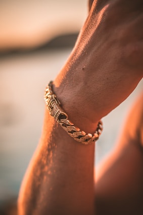 Artistic shot of layered gold and emerald bracelets on a graceful wrist.