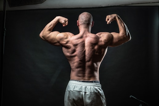 a man flexing his muscles in front of a black background