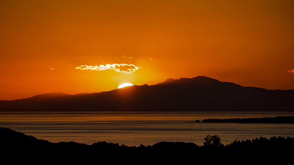 the sun is setting over a mountain range