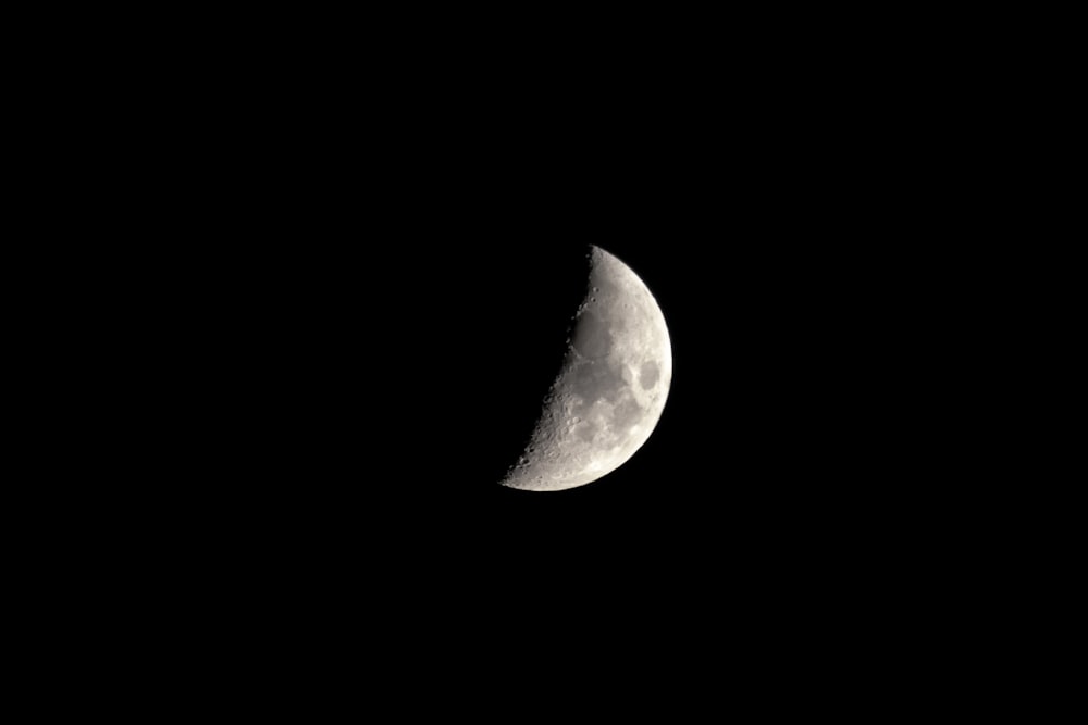 a half moon is seen in the dark sky