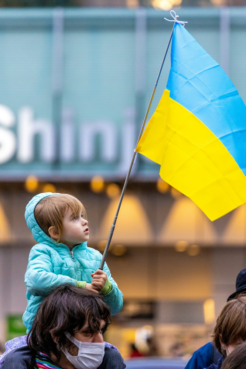 a little girl holding a blue and yellow flag