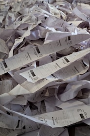 A cluttered desk covered with piles of receipt paper and invoices.