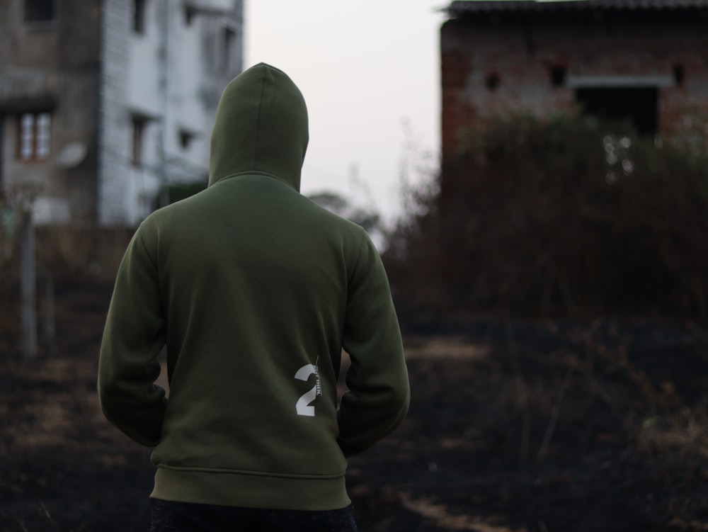 a person in a green hoodie standing in front of a building