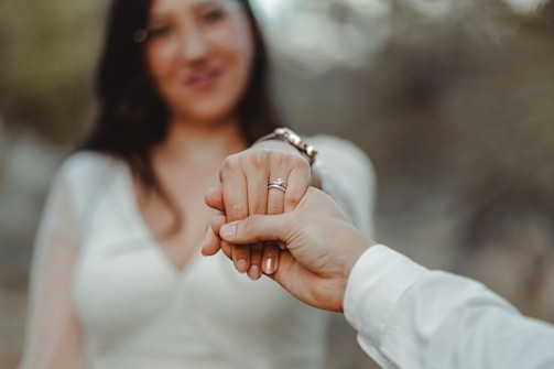 Close-up of a couple holding hands during an intimate engagement shoot in a blooming garden.