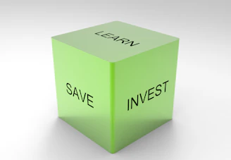 A green 3D cube with the words 'LEARN', 'SAVE', and 'INVEST' on its visible sides, set against a plain white background.