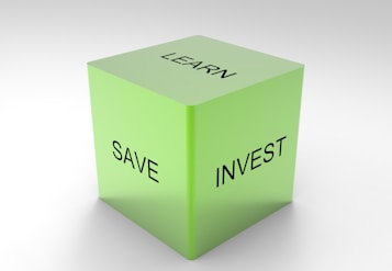A green 3D cube with the words 'LEARN', 'SAVE', and 'INVEST' on its visible sides, set against a plain white background.