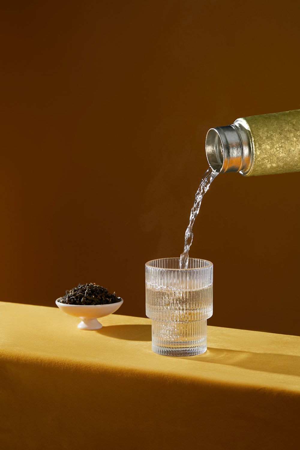 a person pouring water into a glass on a table