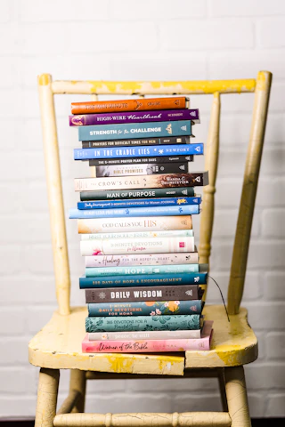 A warm photo of a gently lit stack of Ethel Moore-Barksdale's inspirational books arranged with a cross necklace nearby on a wooden table.