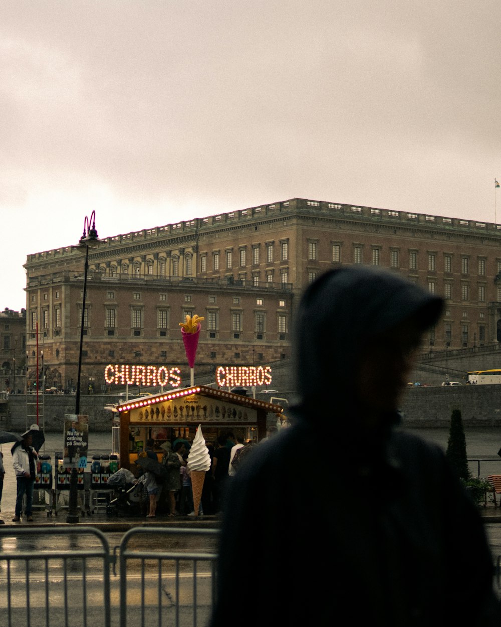 a man in a hooded jacket standing in front of a carousel