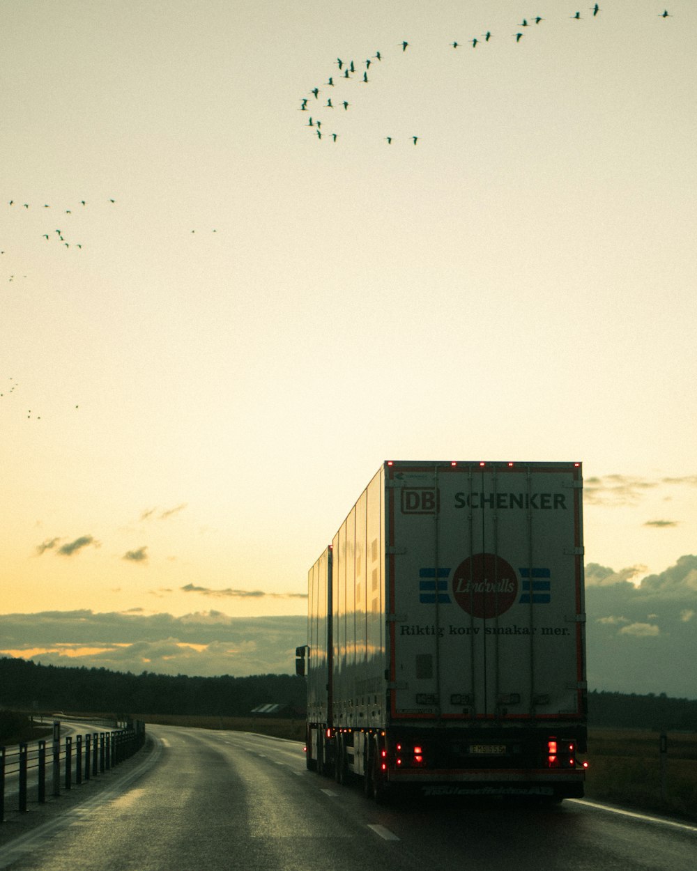 a semi truck driving down a road at sunset