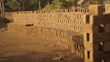 Rows of freshly molded clay bricks drying in sunlight outdoors.