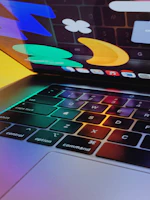 A close-up of hands typing on a laptop with colorful tech icons floating around