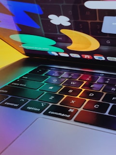 A close-up of hands typing on a laptop with a bright teal screen.