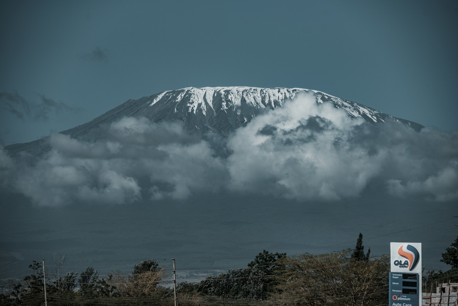 a mountain covered in clouds and a gas station sign