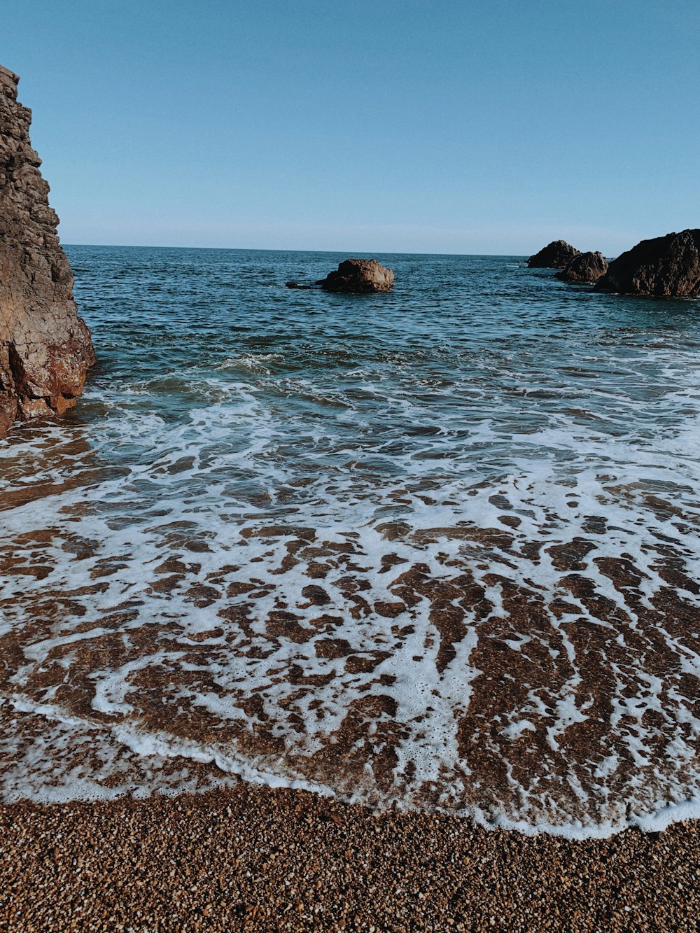 a rocky beach with waves coming in to shore