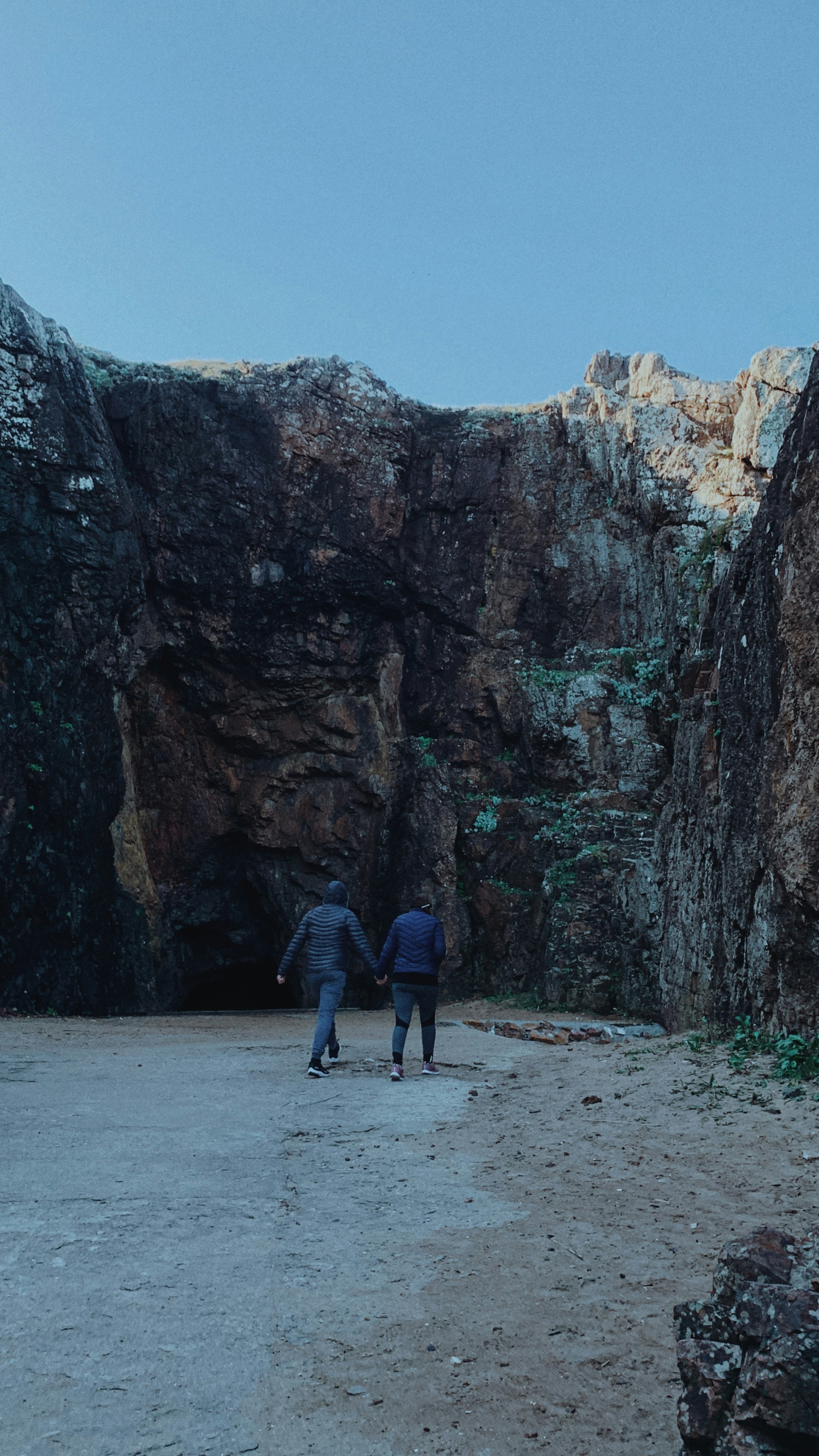 a couple of people walking through a cave
