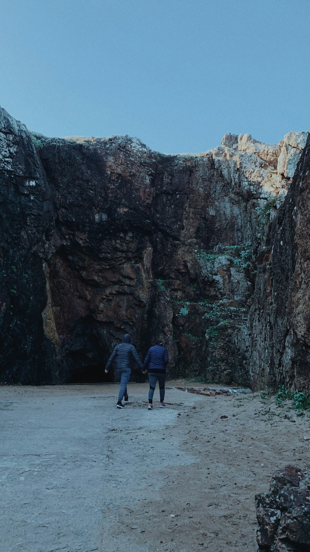 a couple of people walking through a cave