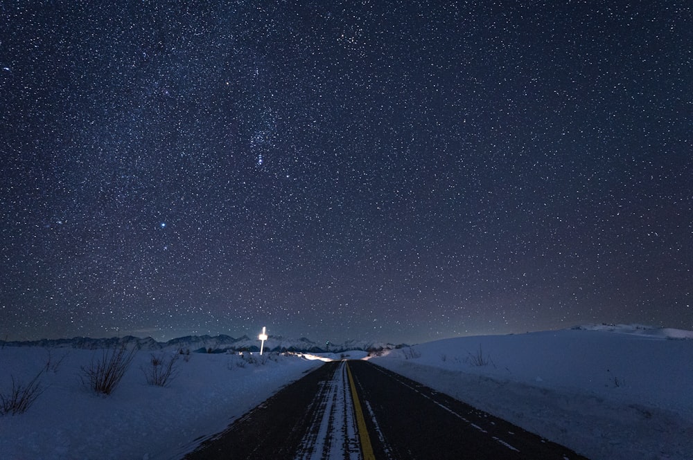 a road with snow and stars in the sky