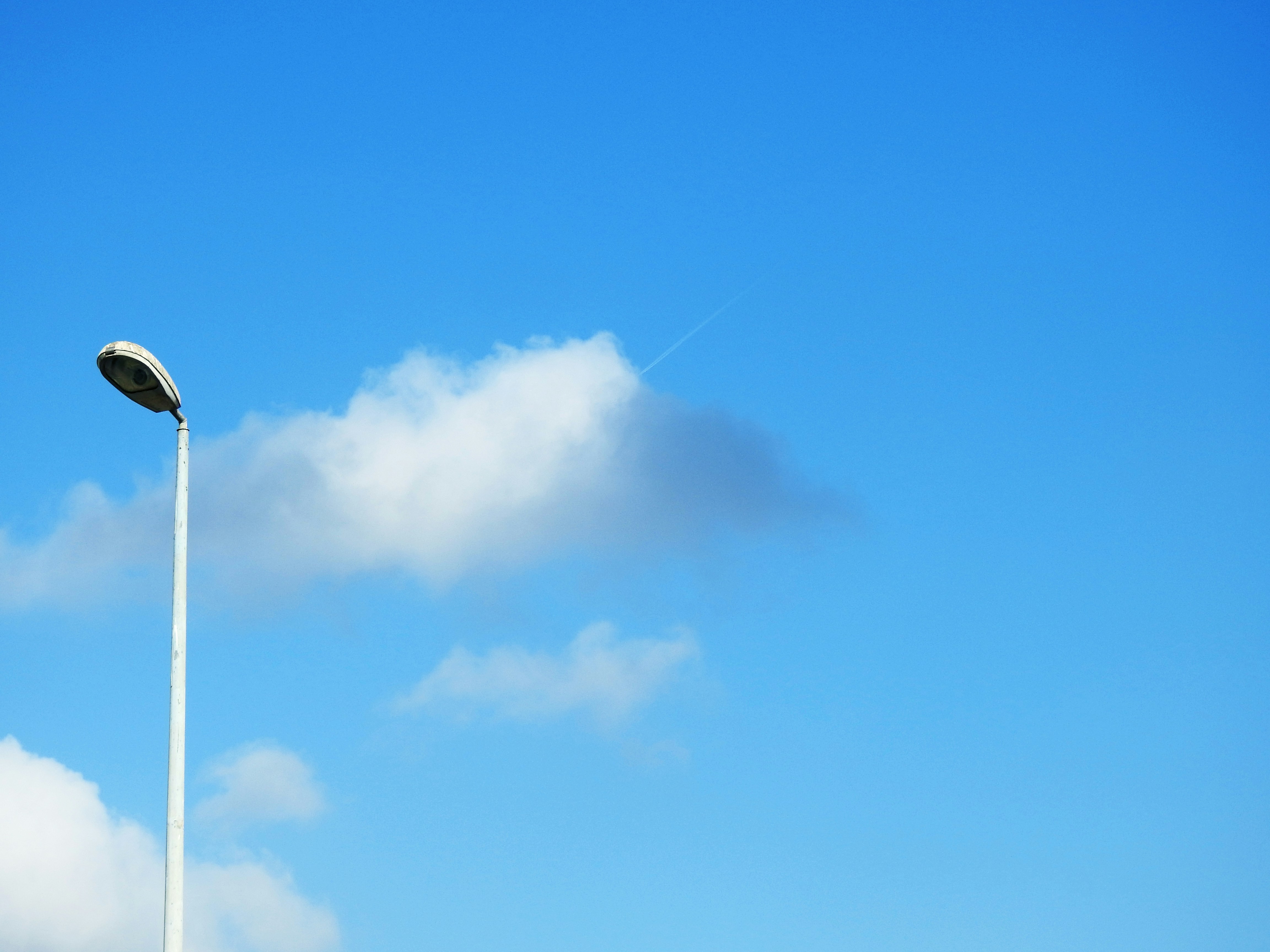 a street light in the middle of a cloud filled sky