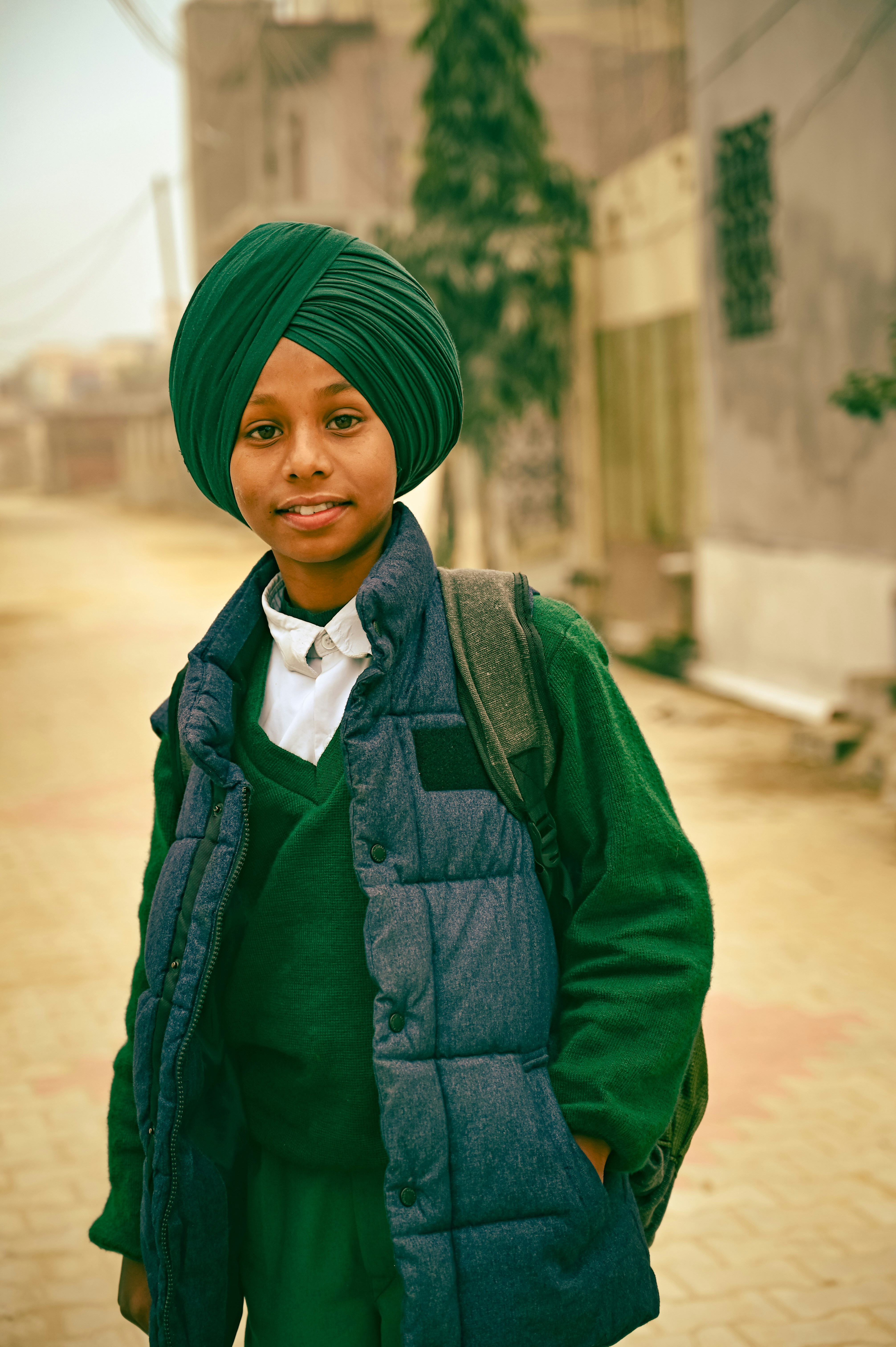 a young boy wearing a green turban and a green vest