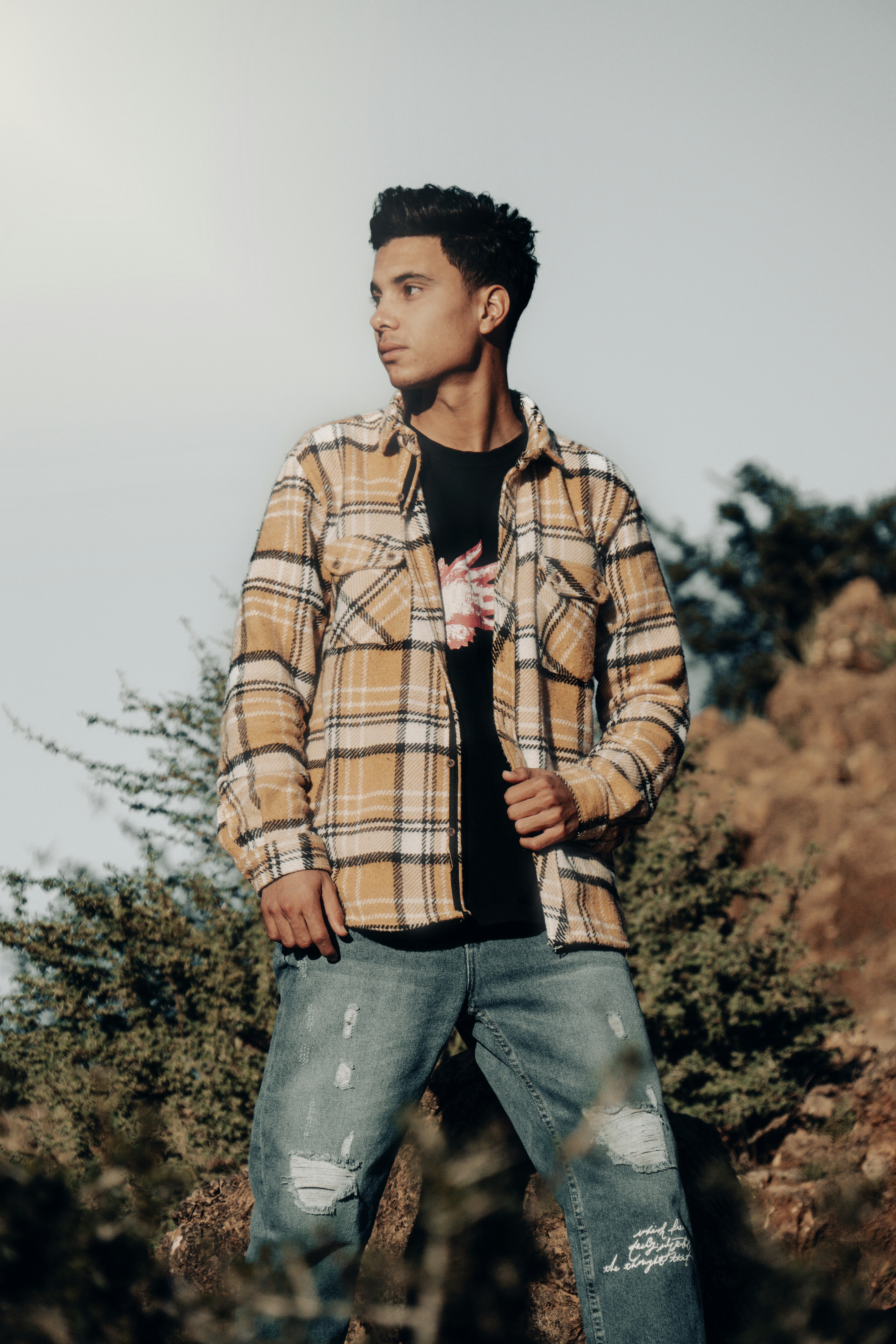a young man standing in a field with trees in the background