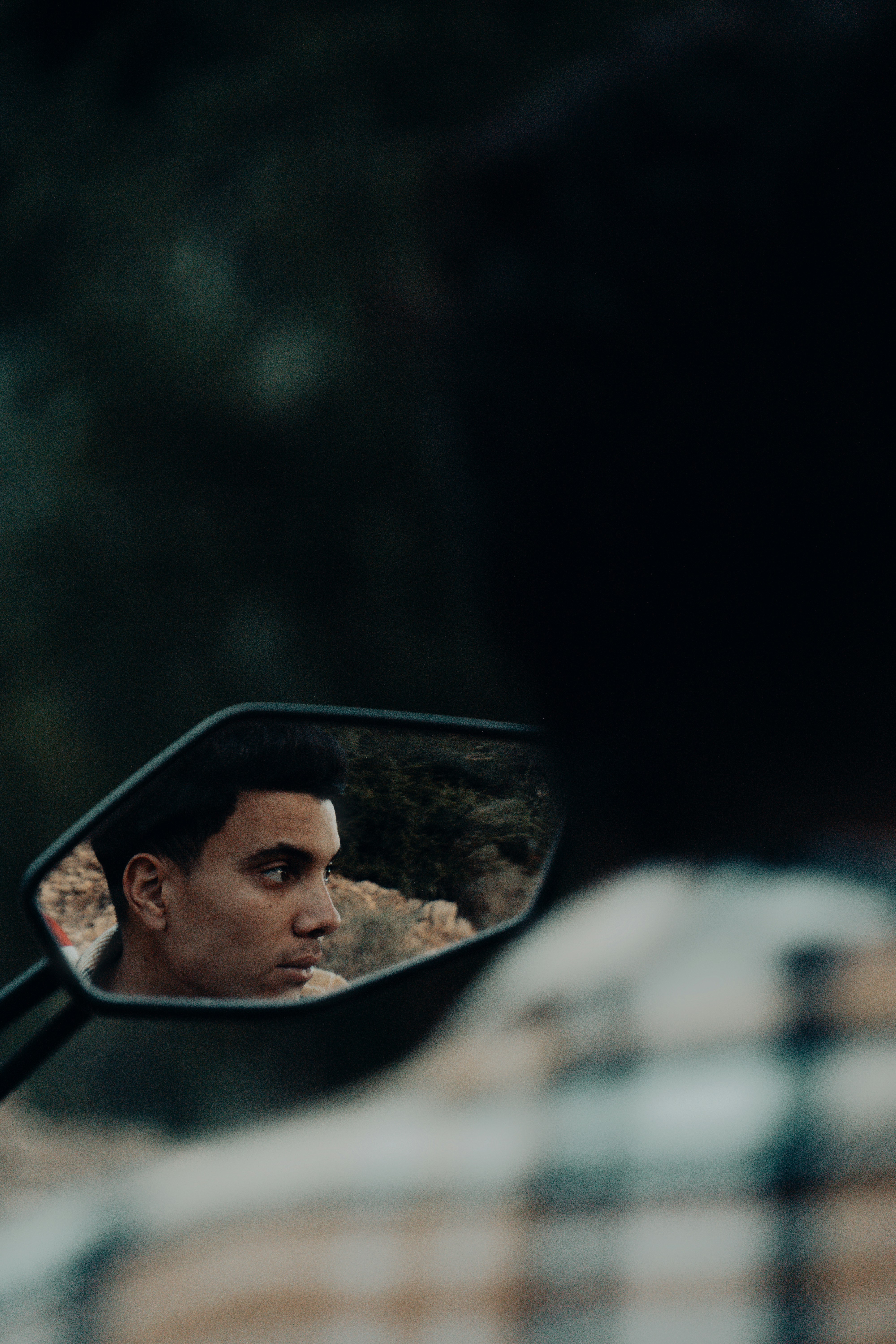 a man's reflection in the side view mirror of a car
