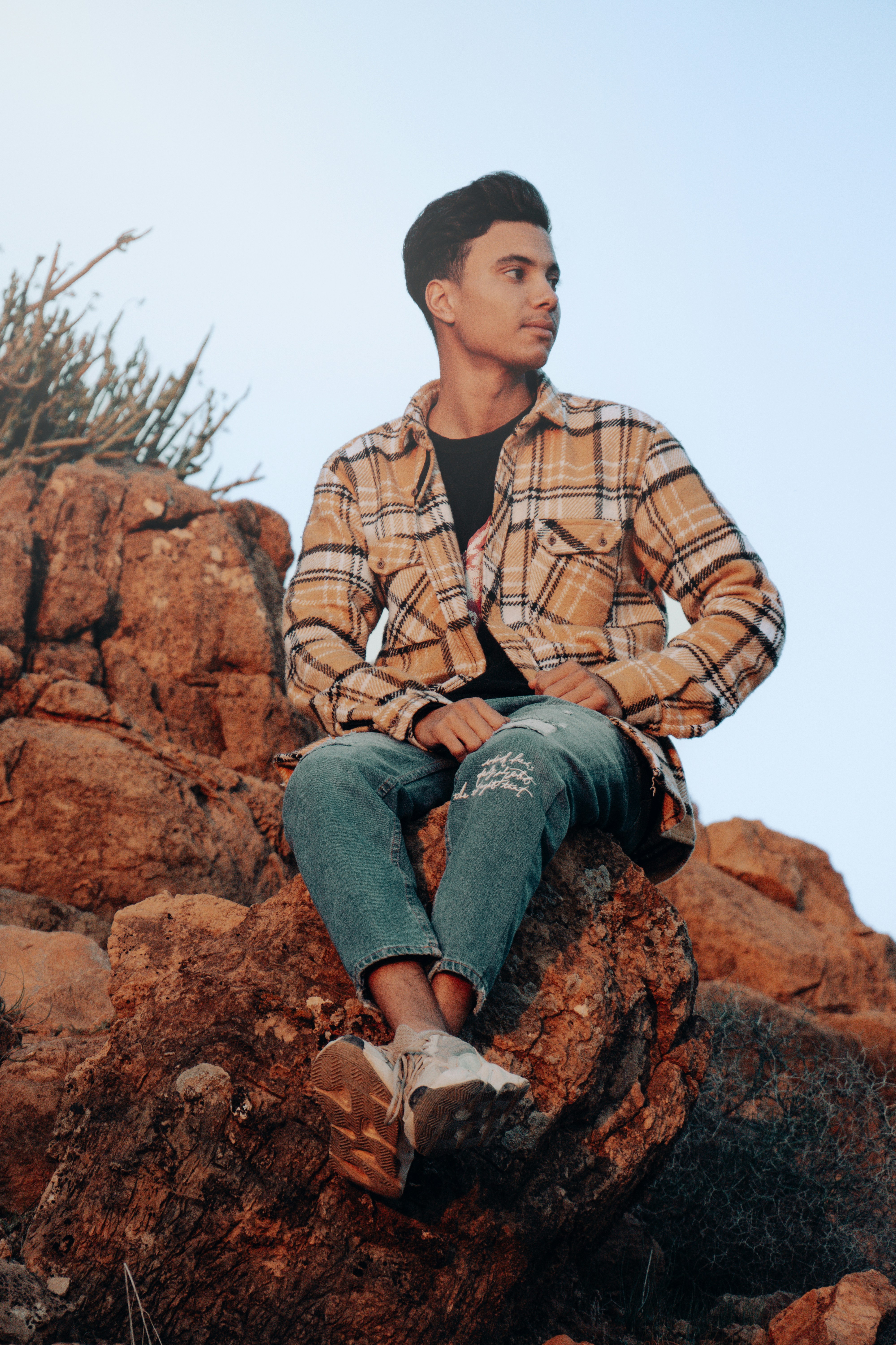 a man sitting on top of a large rock