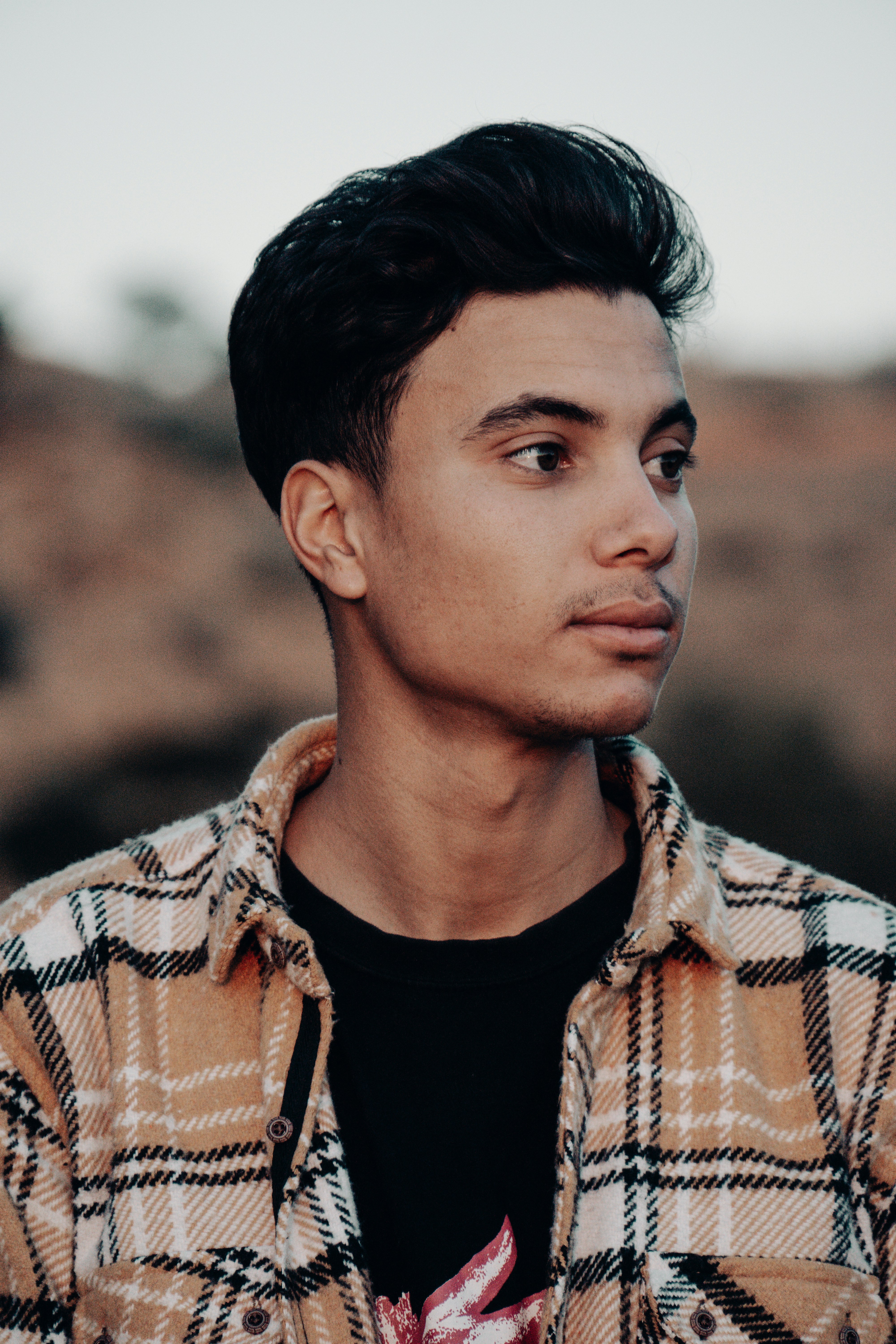 a man in a plaid shirt looks off into the distance