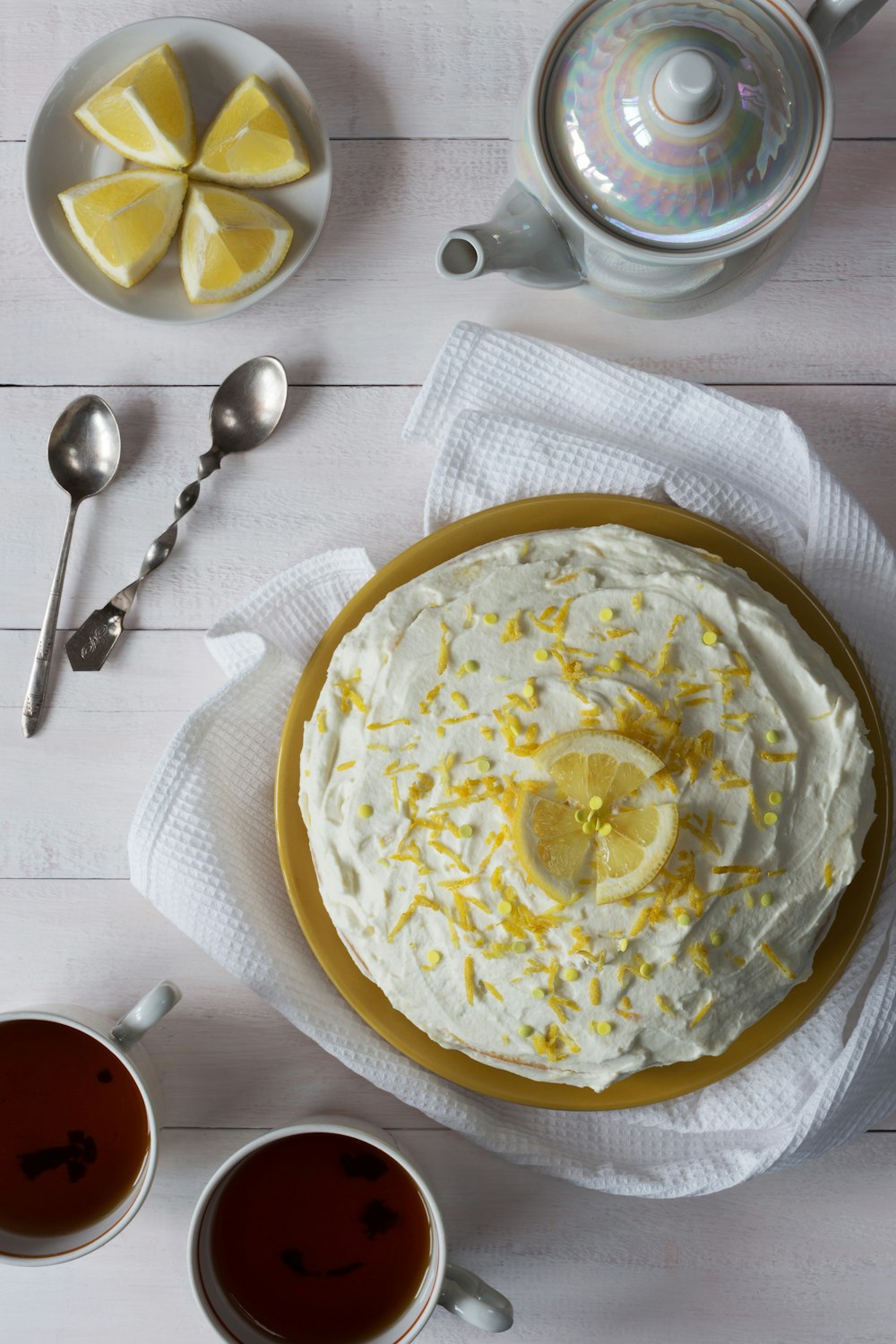 a cake on a plate with lemons and a cup of tea