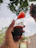 Close-up of a hand holding a glass of golden mezcal with agave plants in the background.