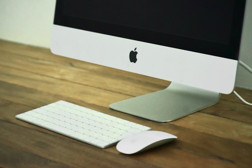 un monitor de computadora y un teclado en un escritorio de madera