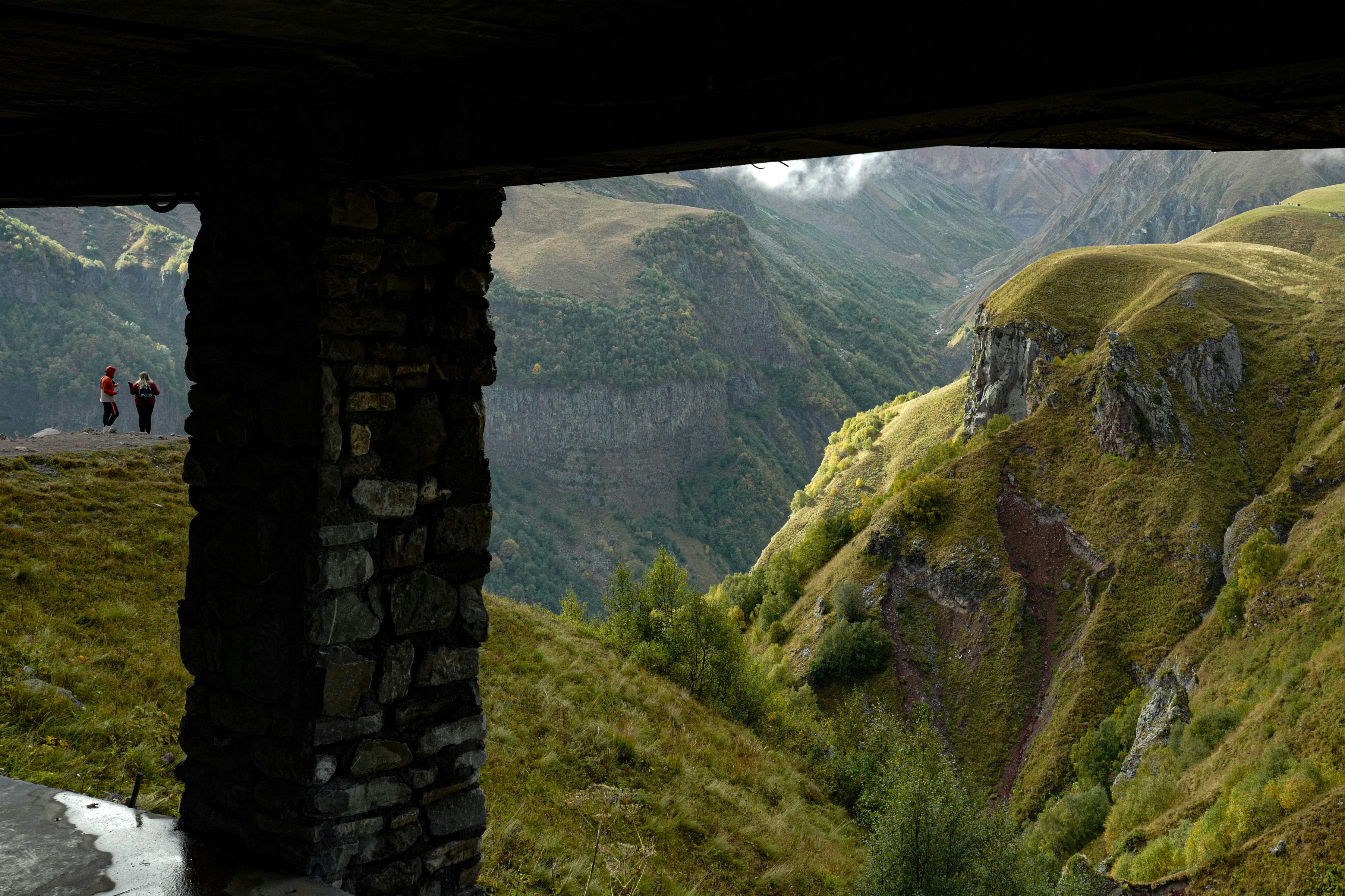 Un par de personas de pie en la cima de una exuberante ladera verde