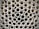 A close-up view of a large stack of uniform, cylindrical pipes arranged in a tightly packed, orderly pattern. The pipes are aligned vertically, creating a repetitive geometric design with circular openings visible.