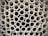 A close-up view of a large stack of uniform, cylindrical pipes arranged in a tightly packed, orderly pattern. The pipes are aligned vertically, creating a repetitive geometric design with circular openings visible.