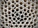 A close-up view of a large stack of uniform, cylindrical pipes arranged in a tightly packed, orderly pattern. The pipes are aligned vertically, creating a repetitive geometric design with circular openings visible.