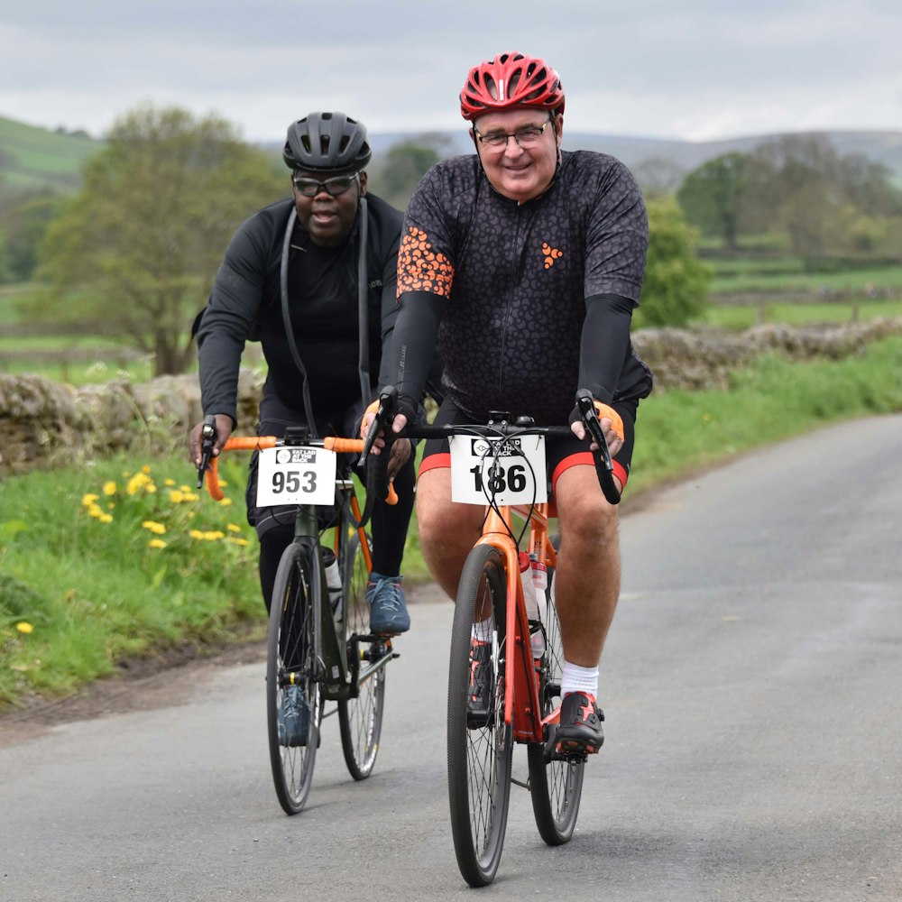 two men riding bikes down a country road