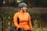 a woman in an orange jacket with a bike helmet