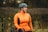 a woman in an orange jacket with a bike helmet