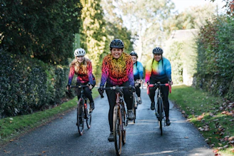 A diverse group of young people cycling together on a sunny day, smiling and supporting each other.