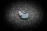 Close-up of a finely crafted magic gimmick resting on a smooth, off-white surface with deep charcoal shadows.