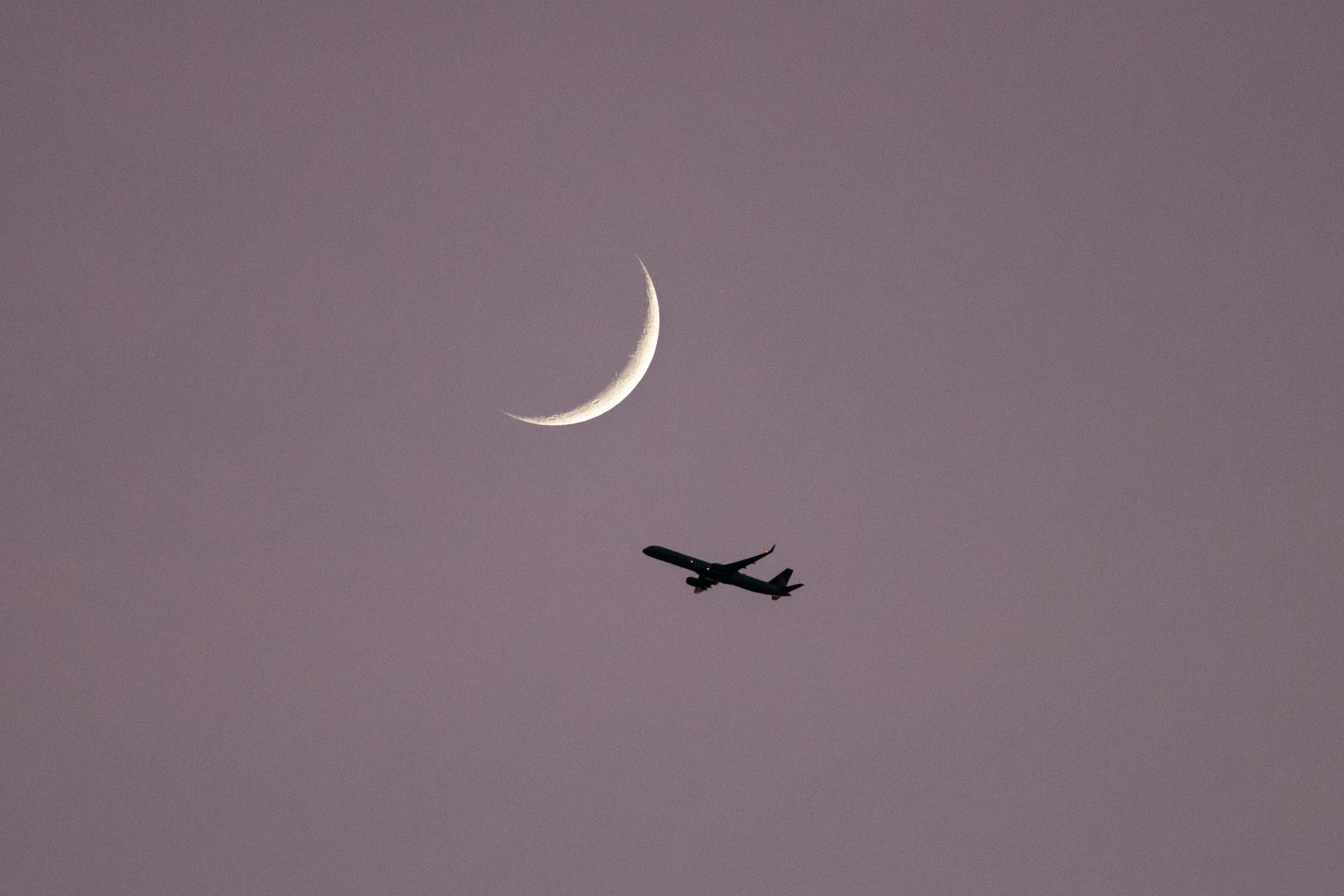 Ein Flugzeug fliegt am Himmel mit dem Mond im Hintergrund