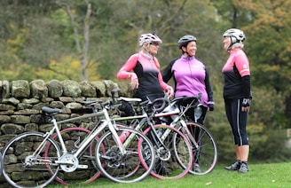 a group of women standing next to each other near a stone wall