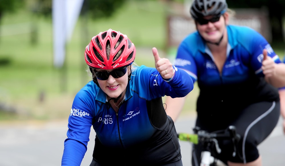 a man and a woman on bicycles giving thumbs up