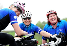 a group of women riding bikes on top of a lush green field