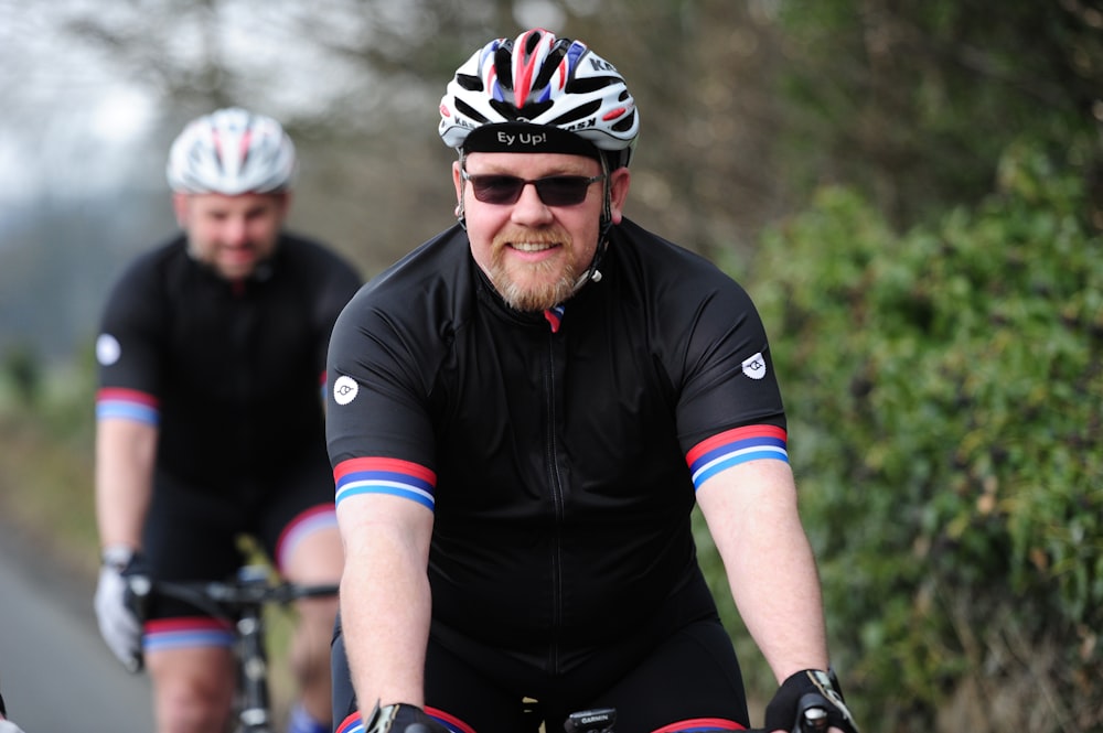 a couple of men riding bikes down a road