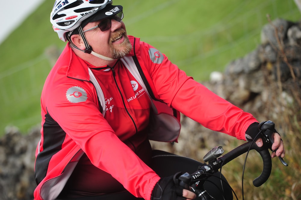 a man in a red jacket riding a bike