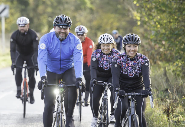 A diverse group of young people cycling together on a sunny day, smiling and enjoying the outdoors.
