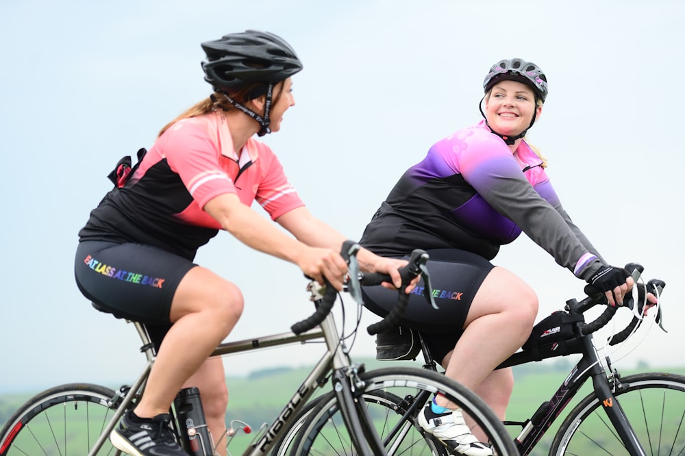 a couple of women riding on the back of bikes