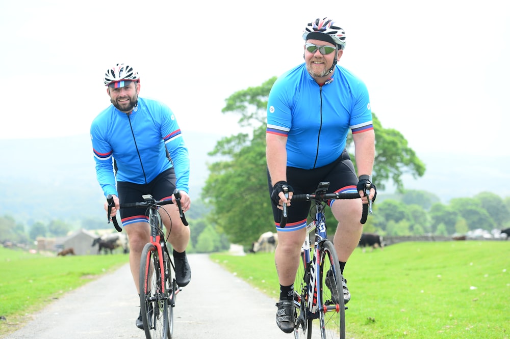 a couple of men riding bikes down a road